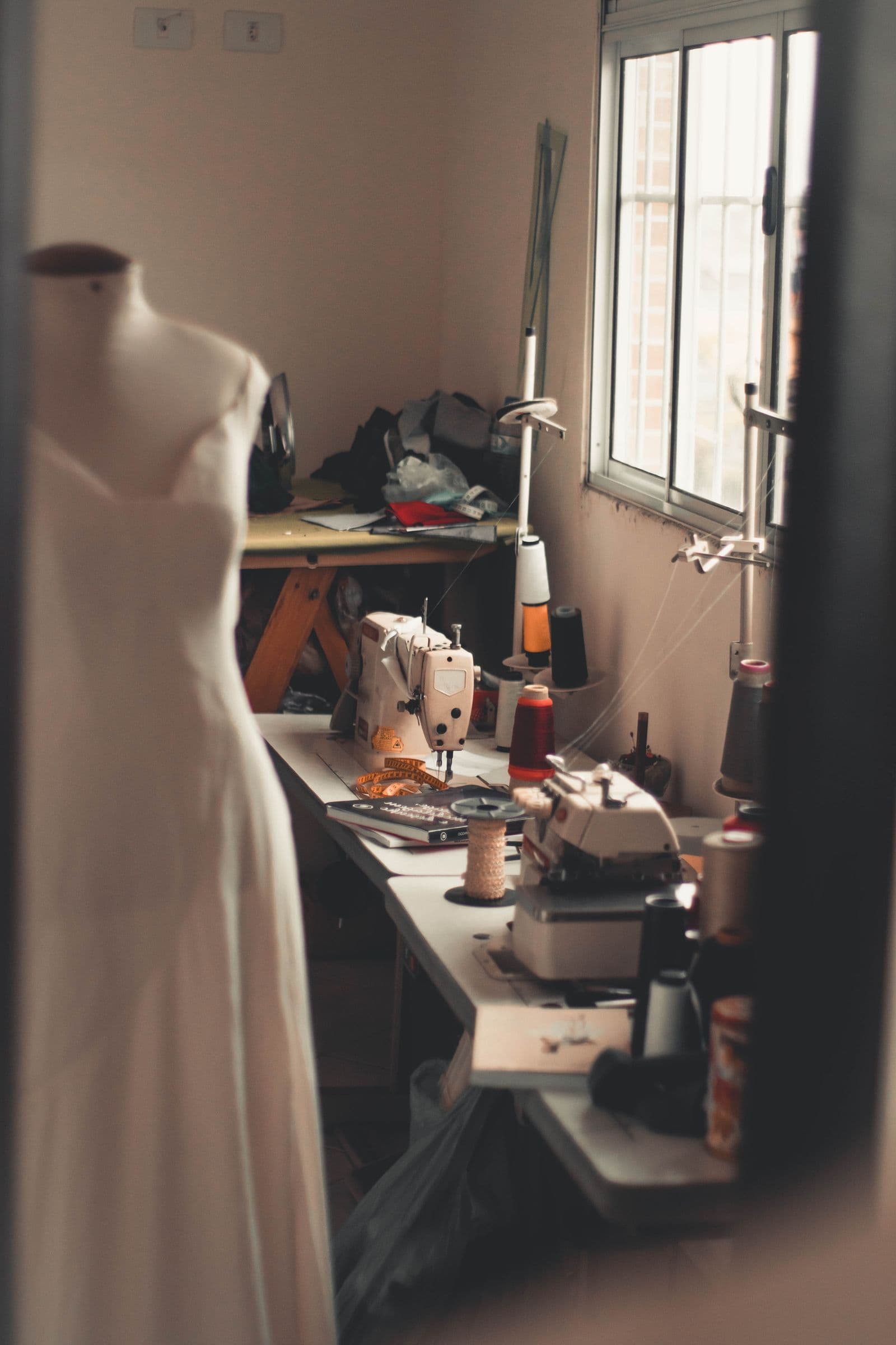 Ateliê de confecção: peças de roupa penduradas e mesa de corte